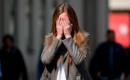 Девушка закрыла глаза руками на улице